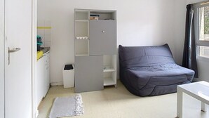 A bedroom with a bed, a white table, a grey wardrobe, and a window with curtains. - Le Wellington, Arras (Arras)