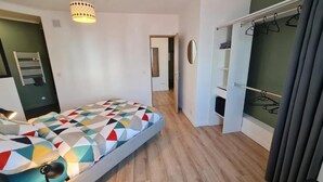 A bedroom with a bed, a hanging light fixture, a wardrobe, and a mirror. - The Scottman House (Arras)