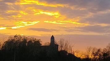 Ein Sonnenuntergang über einem Wiesenfeld, im Hintergrund ein Turm.