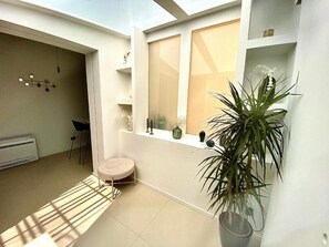 A modern interior with a skylight, a potted plant, and a small seating area.