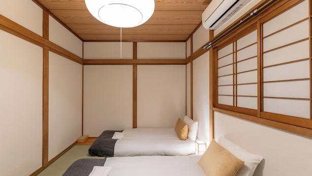 Une pièce de style japonais traditionnel, dotée de deux lits, d’un sol recouvert de tatamis et d’un paravent shoji.
