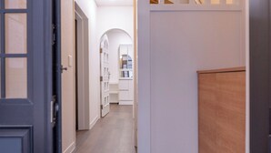 Un couloir doté d’un plancher en bois, de murs blancs et d’un escalier avec des balustrades blanches.