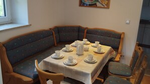 A dining area with a table set for four, surrounded by upholstered chairs with a geometric pattern. - Ferienhaus König - Large house for a large family (Kulmain)