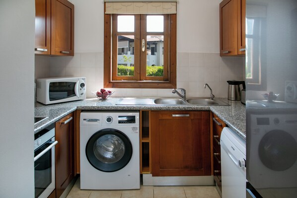 Una cocina compacta equipada con lavadora, microondas y lavaplatos.