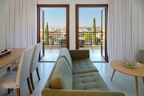 Una sala de estar moderna con un sofá, sillas, una mesa de comedor y un balcón con vistas.