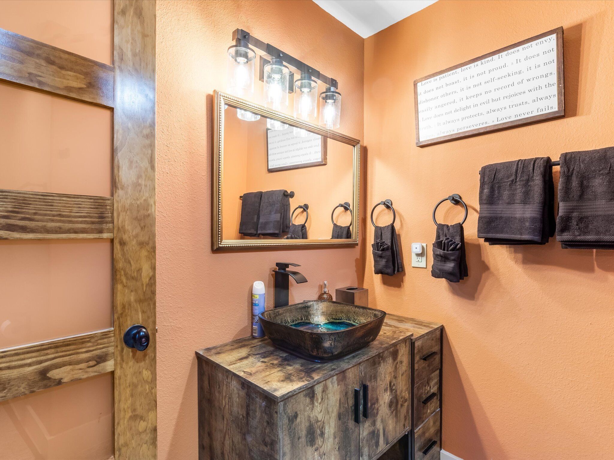 A bathroom with a wooden vanity, a large mirror, and a wall-mounted towel rack.