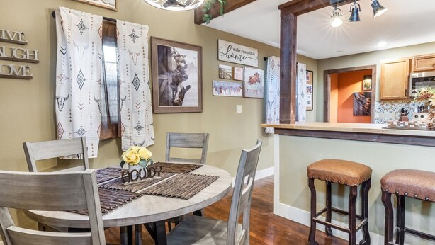 A dining area with a round table, chairs, and a bar with stools. - Stockyards Longhorn House, 1/8 mi to Stockyards-Sleeps up to 11-add 10 next door (Fort Worth)