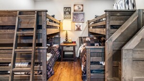 A bunk bed room with wooden bunk beds, a small table with a lamp, and two framed pictures on the wall. - Stockyards Longhorn House, 1/8 mi to Stockyards-Sleeps up to 11-add 10 next door (Fort Worth)