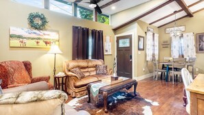 A spacious living room with a high ceiling, a ceiling fan, a fireplace, and a dining area with a chandelier. - Stockyards Longhorn House, 1/8 mi to Stockyards-Sleeps up to 11-add 10 next door (Fort Worth)