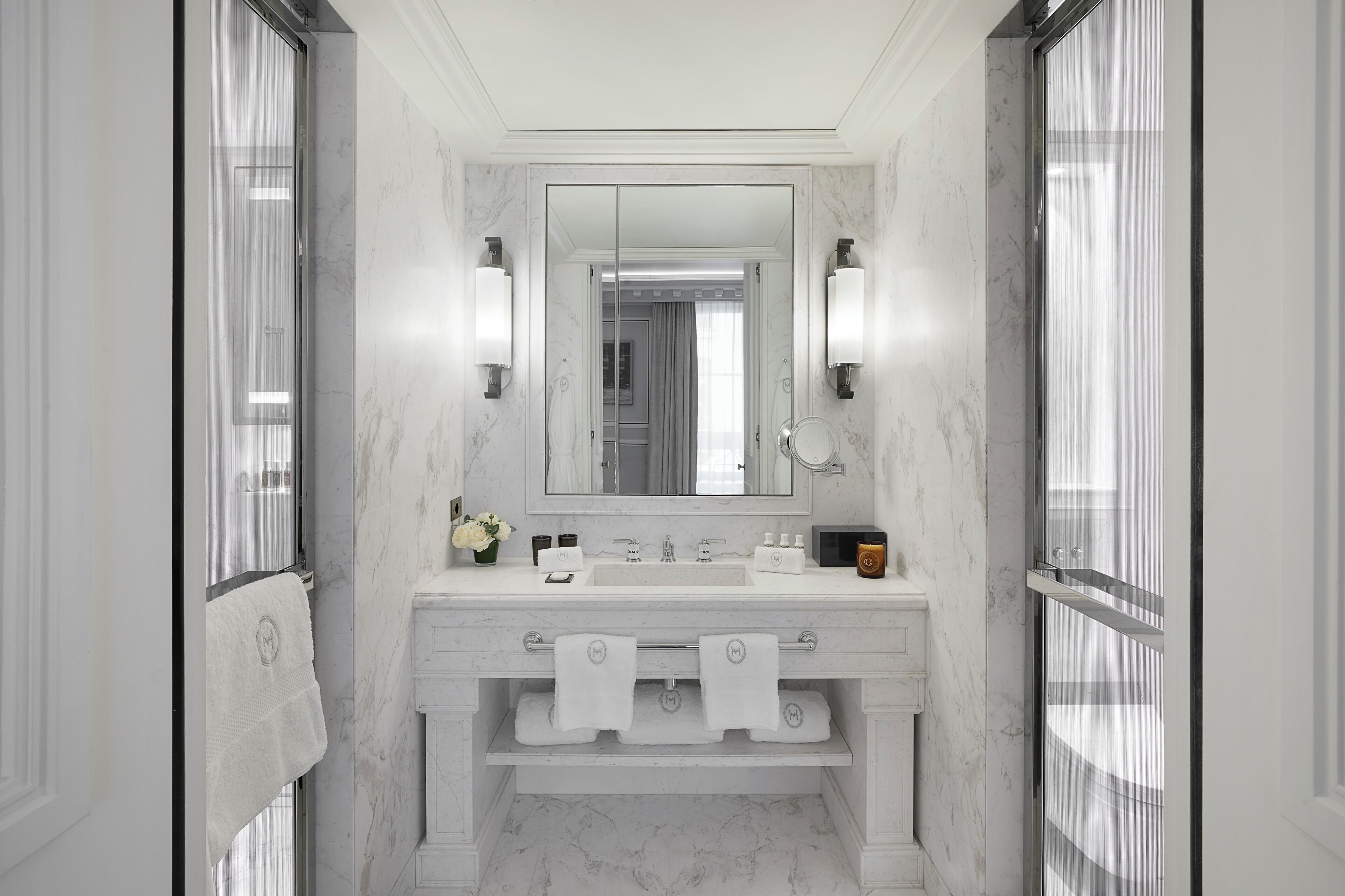 Un baño moderno con tocador de mármol, un espejo grande y dos toalleros.