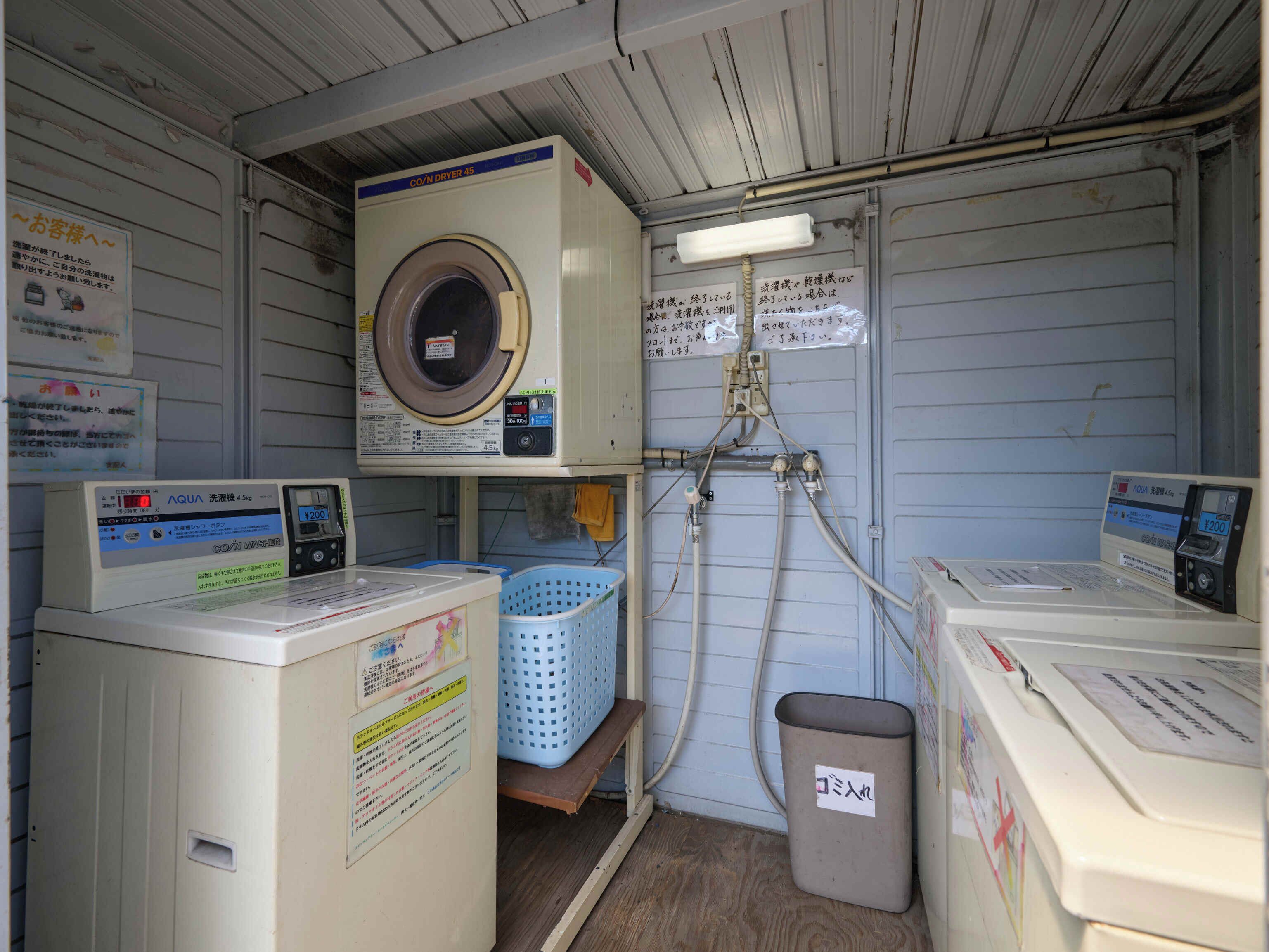 A laundry room with two washing machines, a dryer, and a water heater.