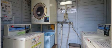 A laundry room with two washing machines, a dryer, and a water heater.