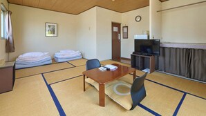 Una habitación con esteras de tatami, techo de madera, televisor, reloj y una puerta.