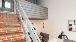 Un intérieur moderne avec un escalier en briques, un coin repas comprenant une table et des chaises, et un canapé.