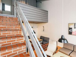 Un interior moderno con una escalera de ladrillo, una zona de comedor con mesa y sillas, y un sofá.