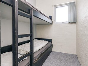 Habitació amb lliteres, finestra i terra amb moqueta.