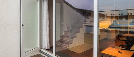 A residential property with a sliding glass door leading to a covered outdoor area with a brick staircase and a dining table.