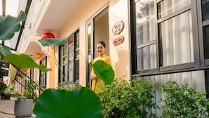 A person standing at the entrance of a building with large windows and a sign that reads "Villa". - Du Yen Hoi An Villa (Da Nang)