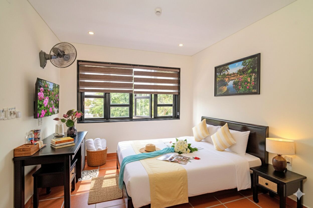 A neatly arranged bedroom with a bed, bedside tables, a fan, and a window with blinds.
