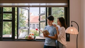 A room with a large window, a table with a book, a rose, and glasses. - Du Yen Hoi An Villa (Da Nang)