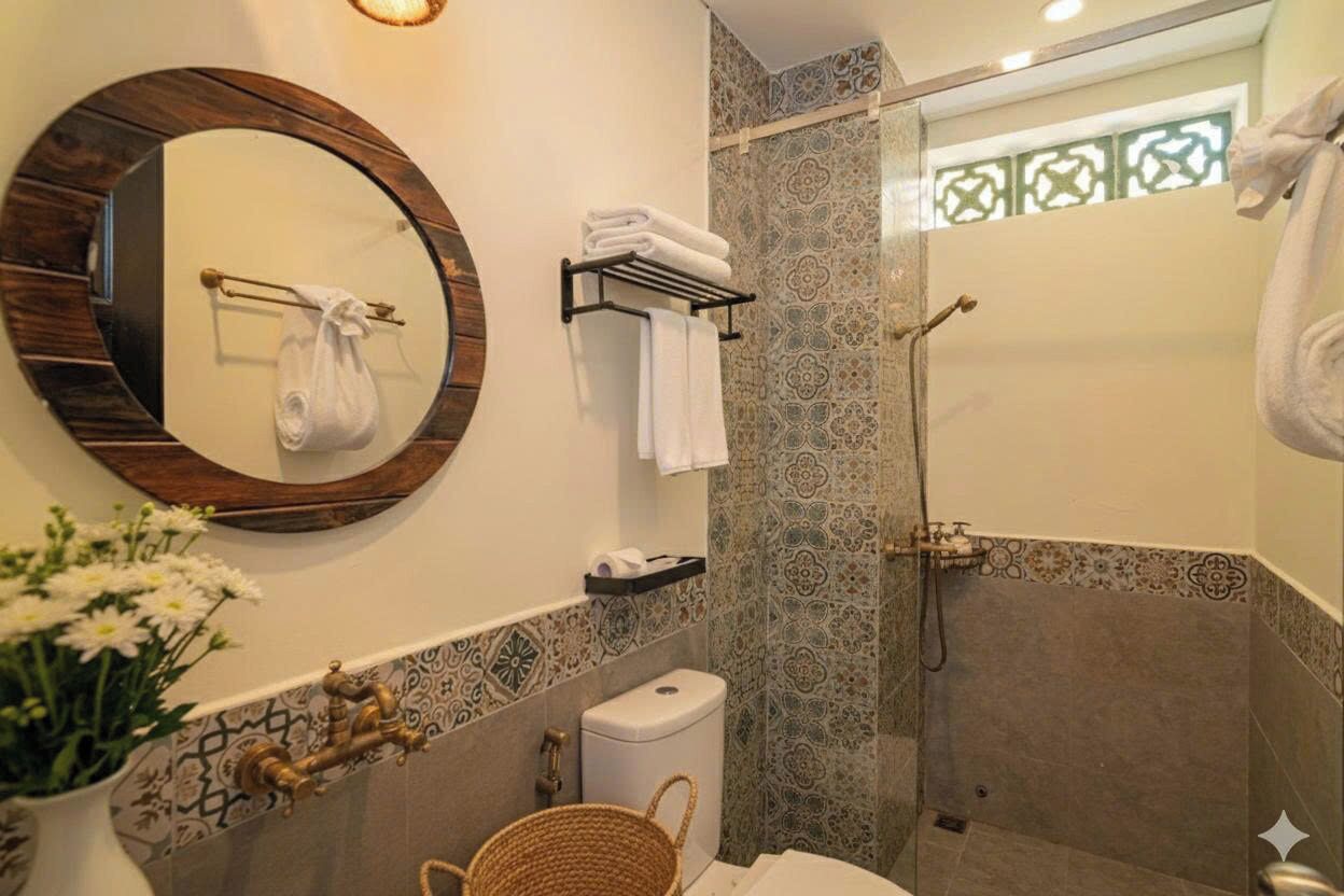 Um banheiro com espelho redondo, vaso sanitário, chuveiro e porta-toalhas.
