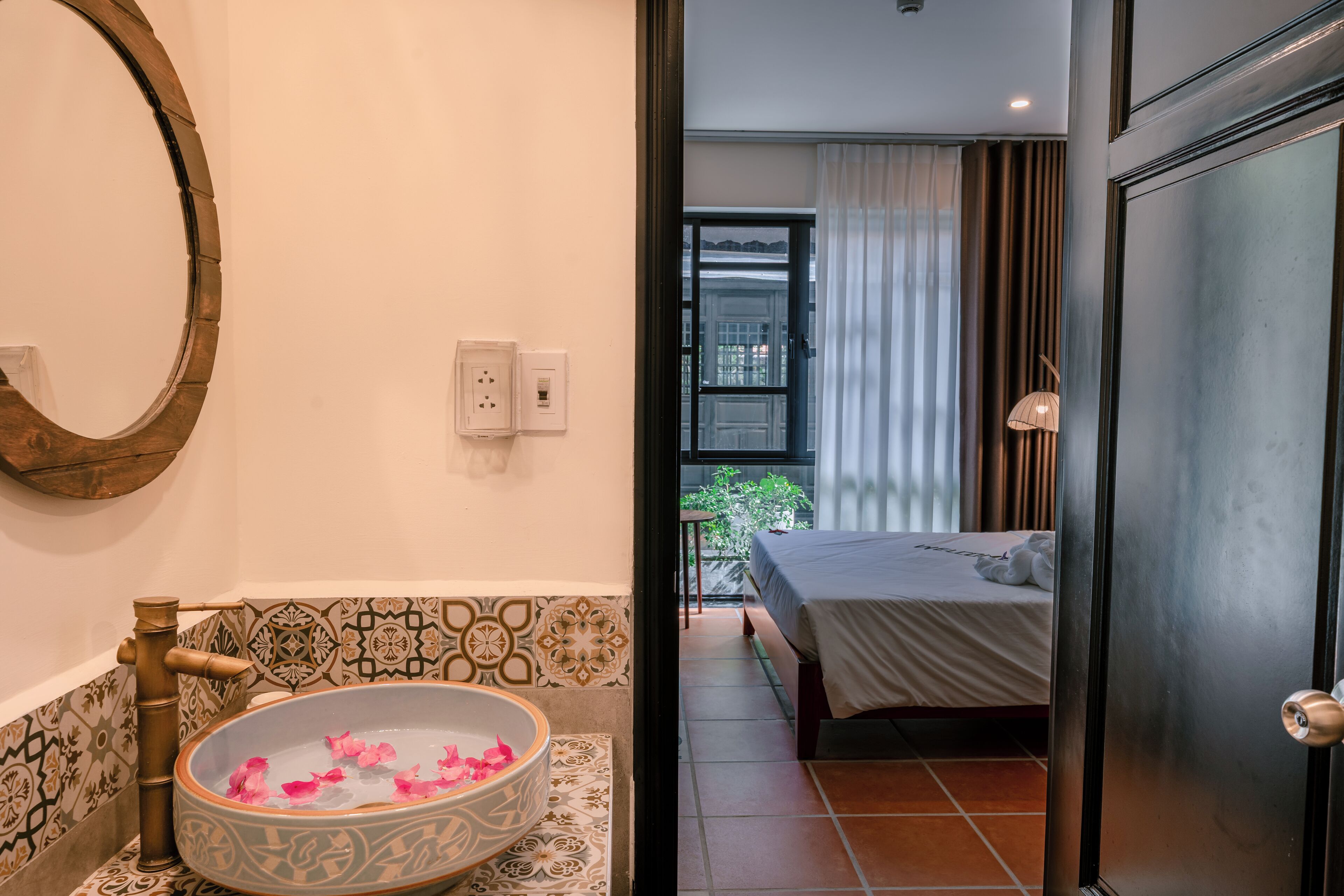 Un baño con una bañera independiente, un espejo y un salpicadero de azulejos estampados.