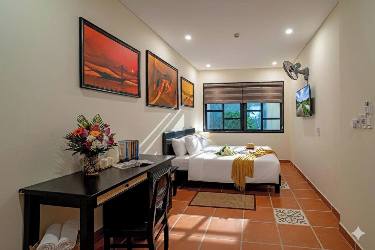 A bedroom with a bed, a desk, a chair, a window with blinds, and artwork on the walls.