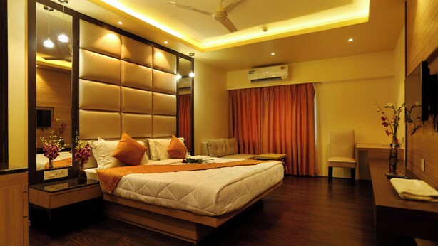 Une chambre d’hôtel moderne équipée d’un grand lit, d’un bureau, d’une chaise, d’un miroir et d’un appareil de climatisation.