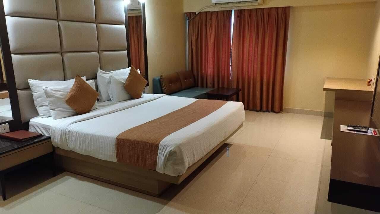 A hotel room with a large bed, a desk, and a sofa.