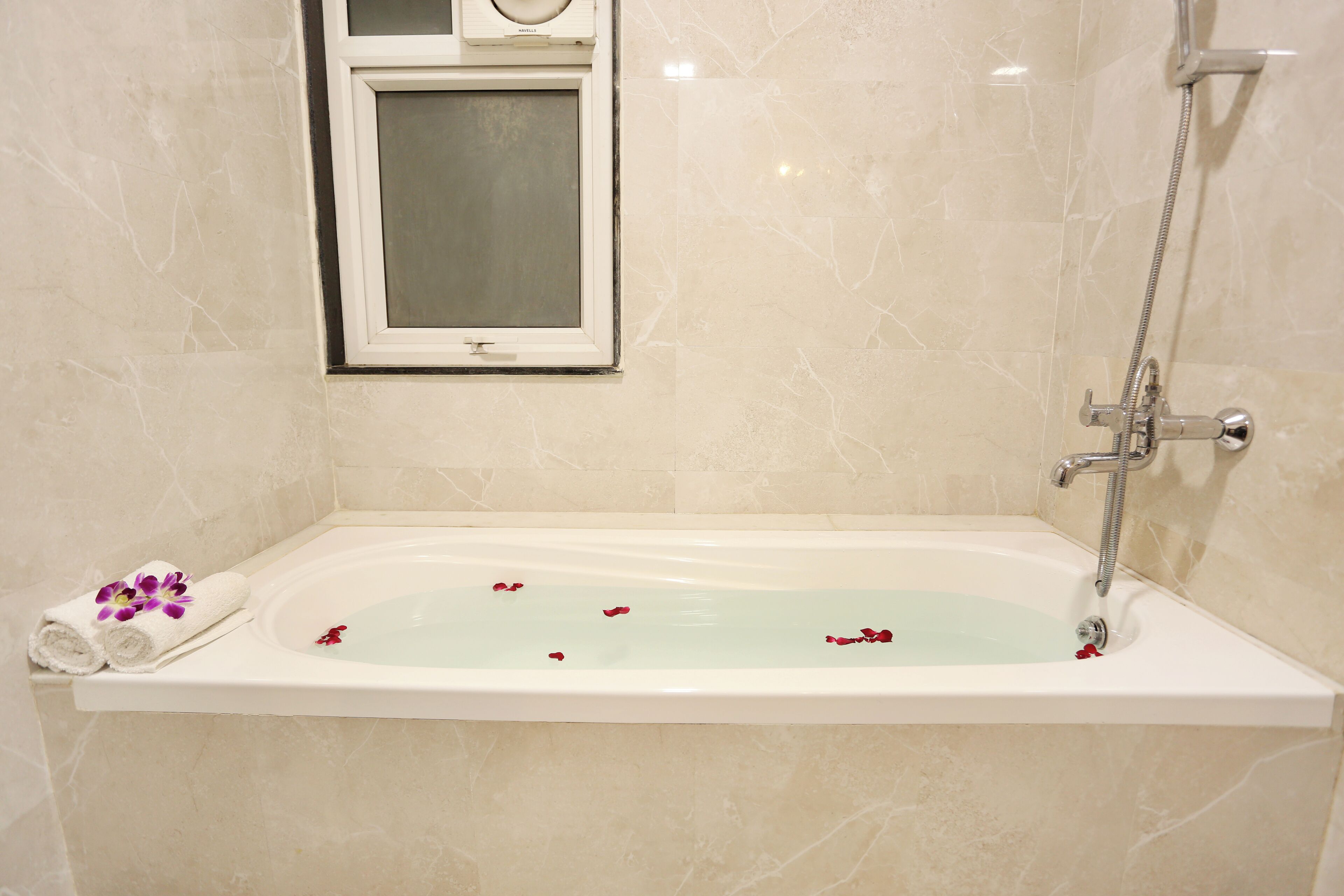 A bathroom with a bathtub, a window, and a shower.