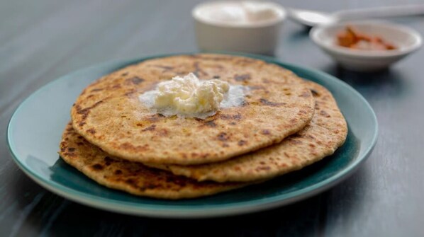 A stack of flatbreads on a plate with a dollop of butter on top.