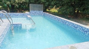 Et rektangulært swimmingpool med blå mosaikfliser og en metalstige.