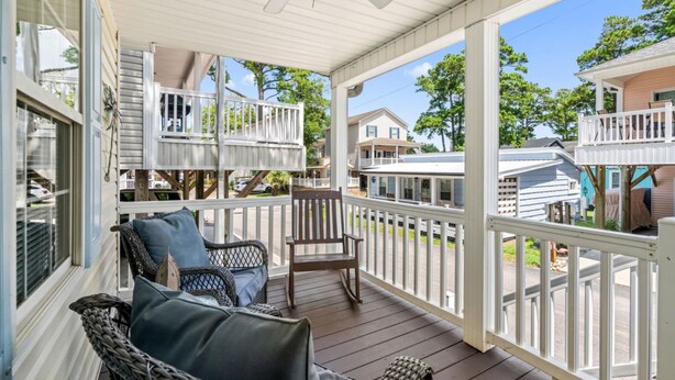 A covered porch with wicker furniture and a ceiling fan.