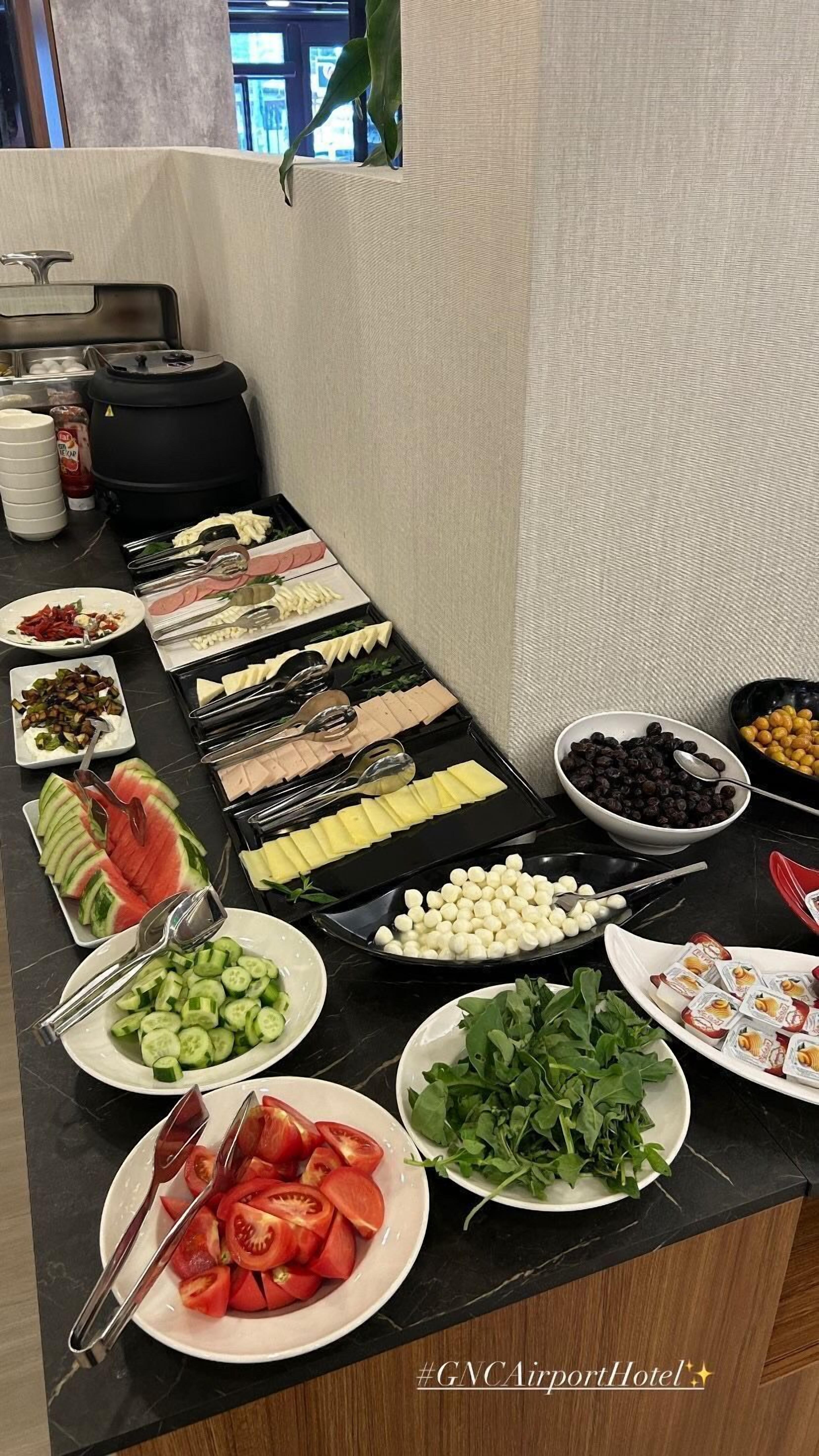 A buffet table with various food items and utensils.