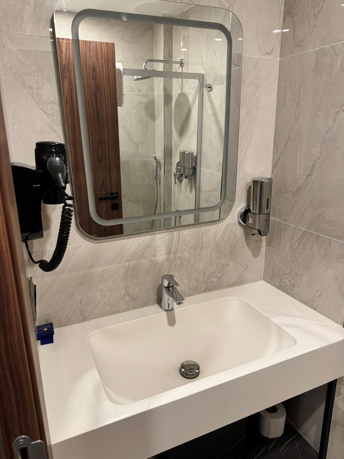 A bathroom with a white sink, a mirror, and a shower enclosure.