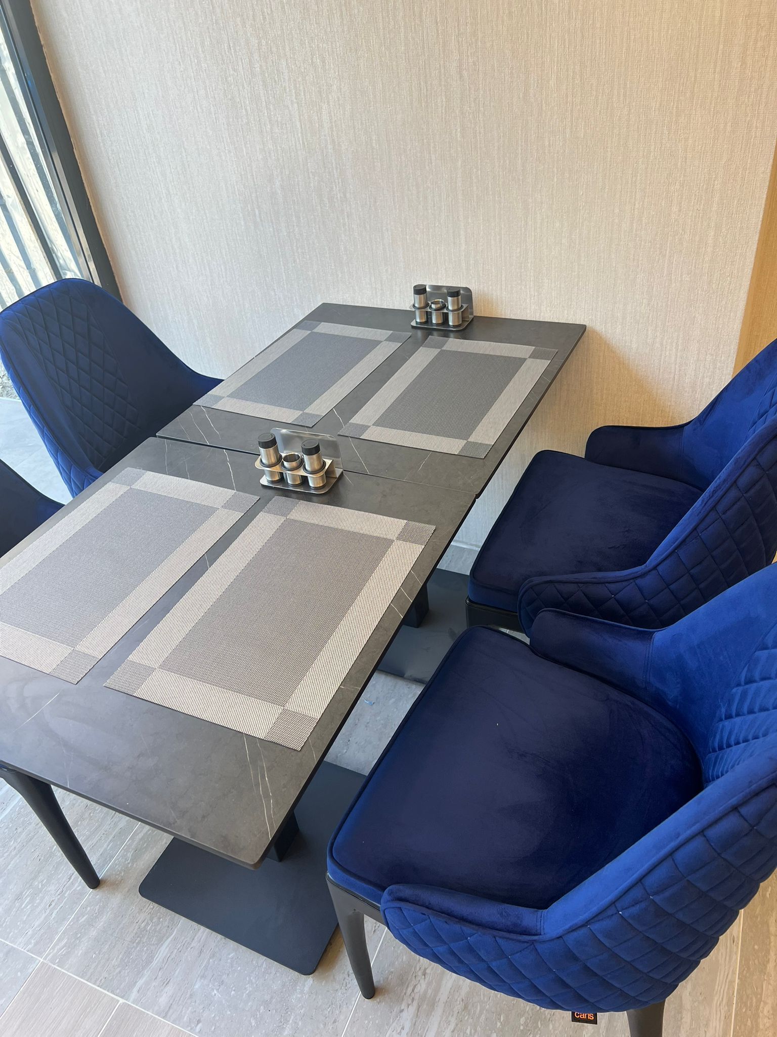 A modern dining area with a rectangular table, blue cushioned chairs, and a patterned table runner.