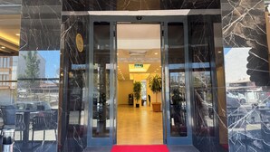 Een hotelentree met een rode loper, glazen deuren en een zicht op het interieur.