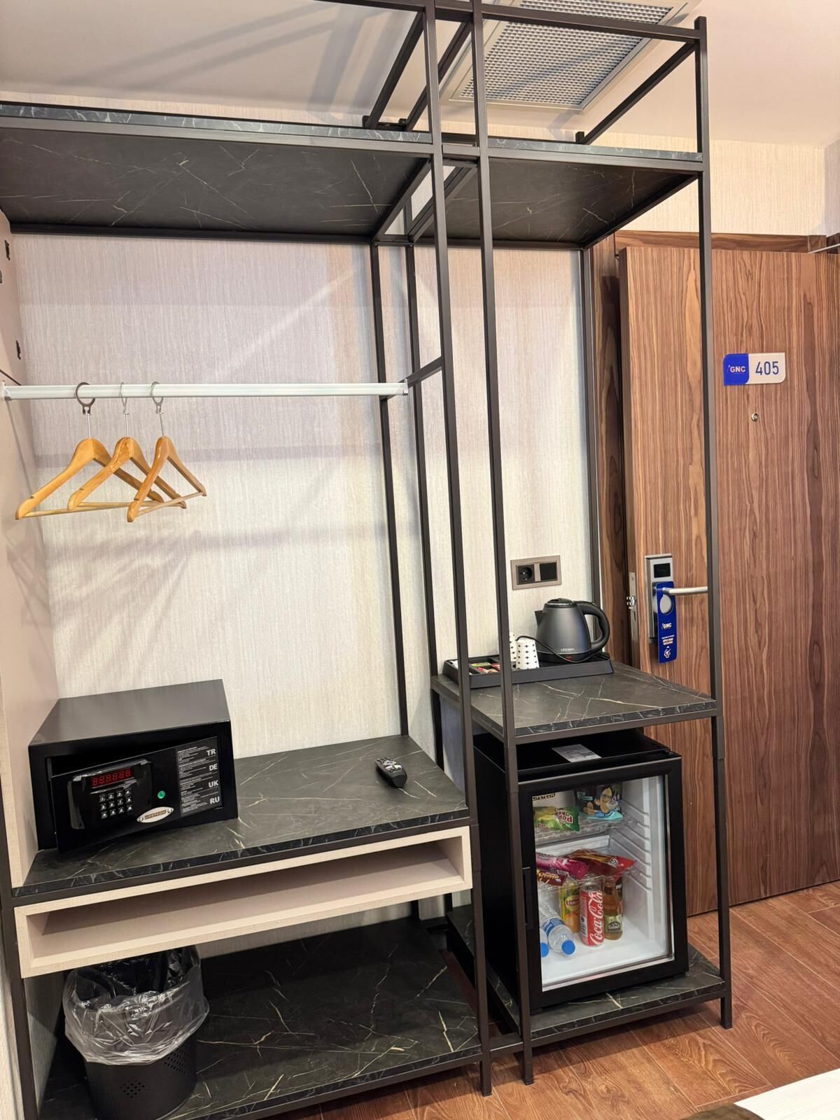 Habitación de hotel compacta con kitchenette, minibar y una pequeña zona de estar.