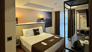 Een moderne hotelkamer met een bed, nachtkastje en een bureau met stoel.