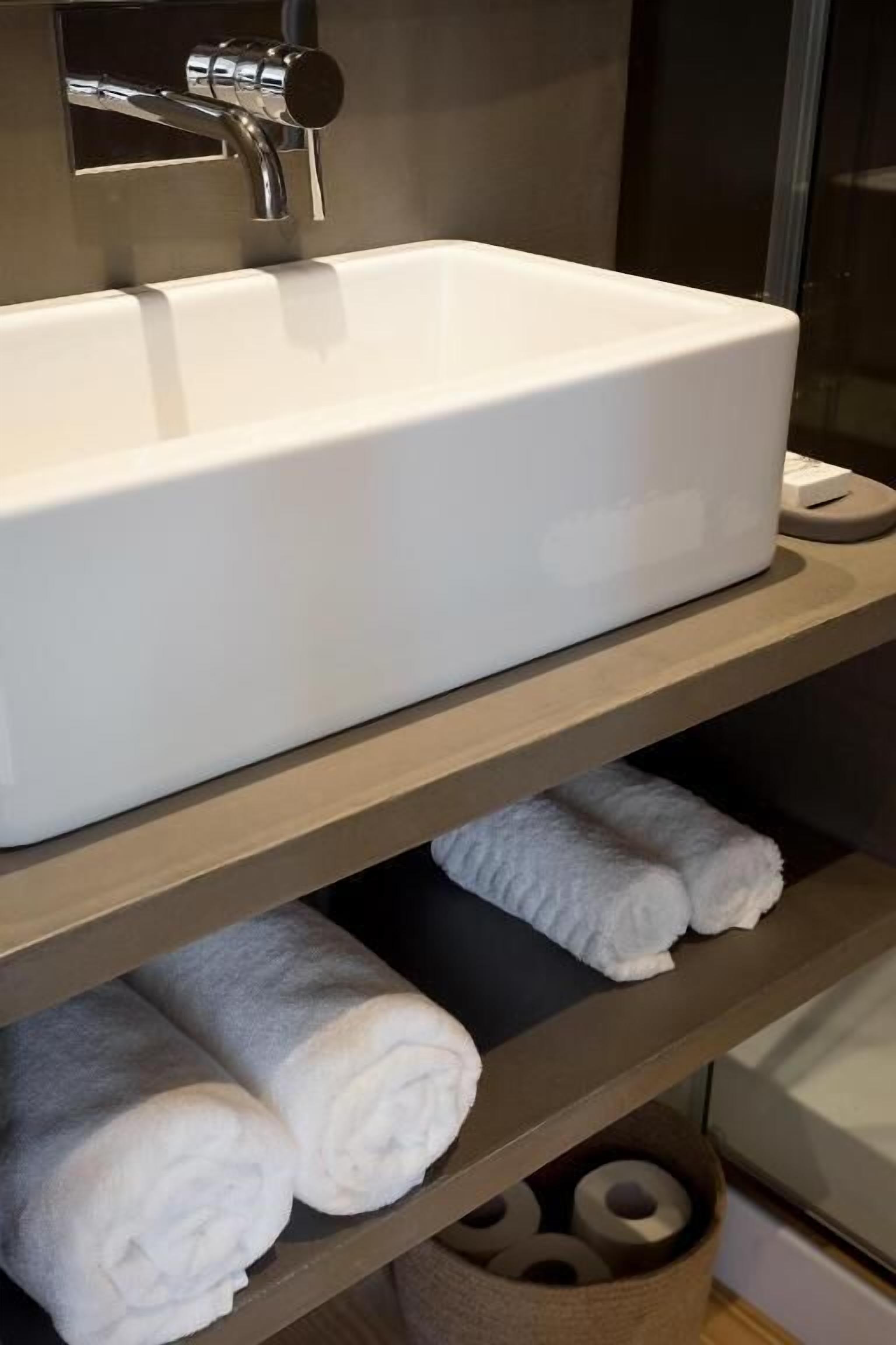 A bathroom with a white sink, a towel rack with towels, and a towel dispenser.