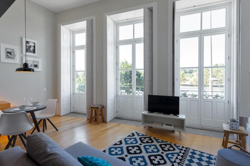 A spacious living area with a sofa, a coffee table, a TV on a stand, and a patterned rug.