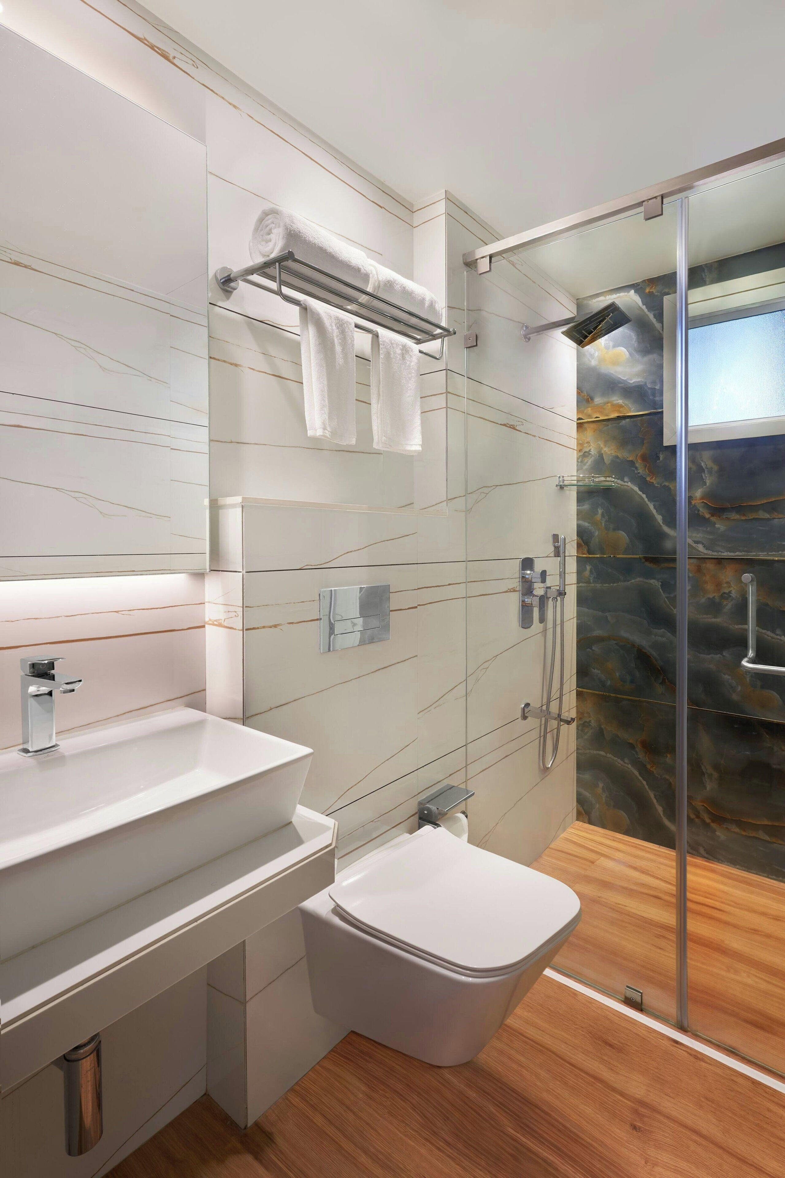 A modern bathroom with a white sink, a toilet, and a glass shower enclosure.