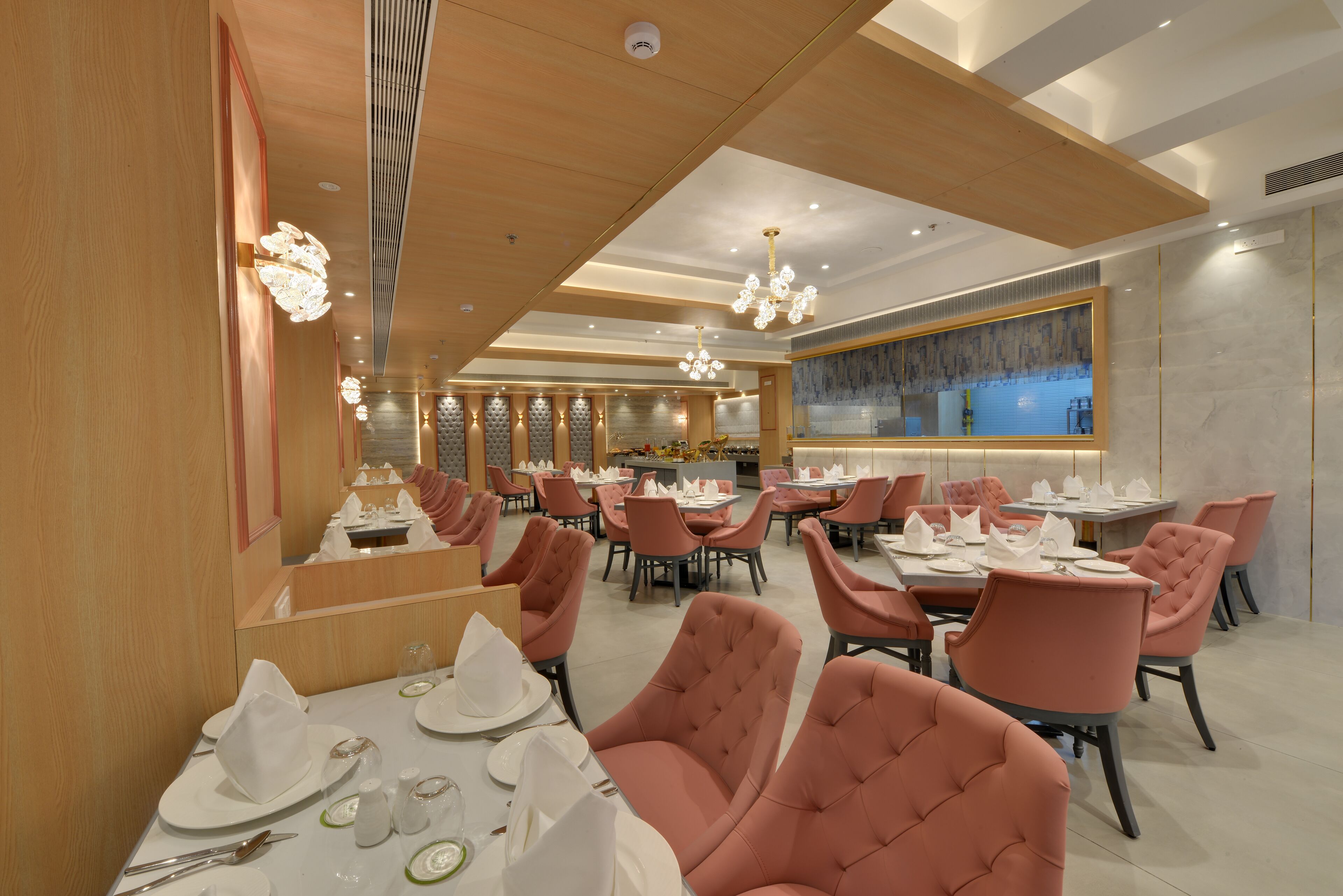 A modern dining area with pink upholstered chairs, white table settings, and a wooden ceiling.