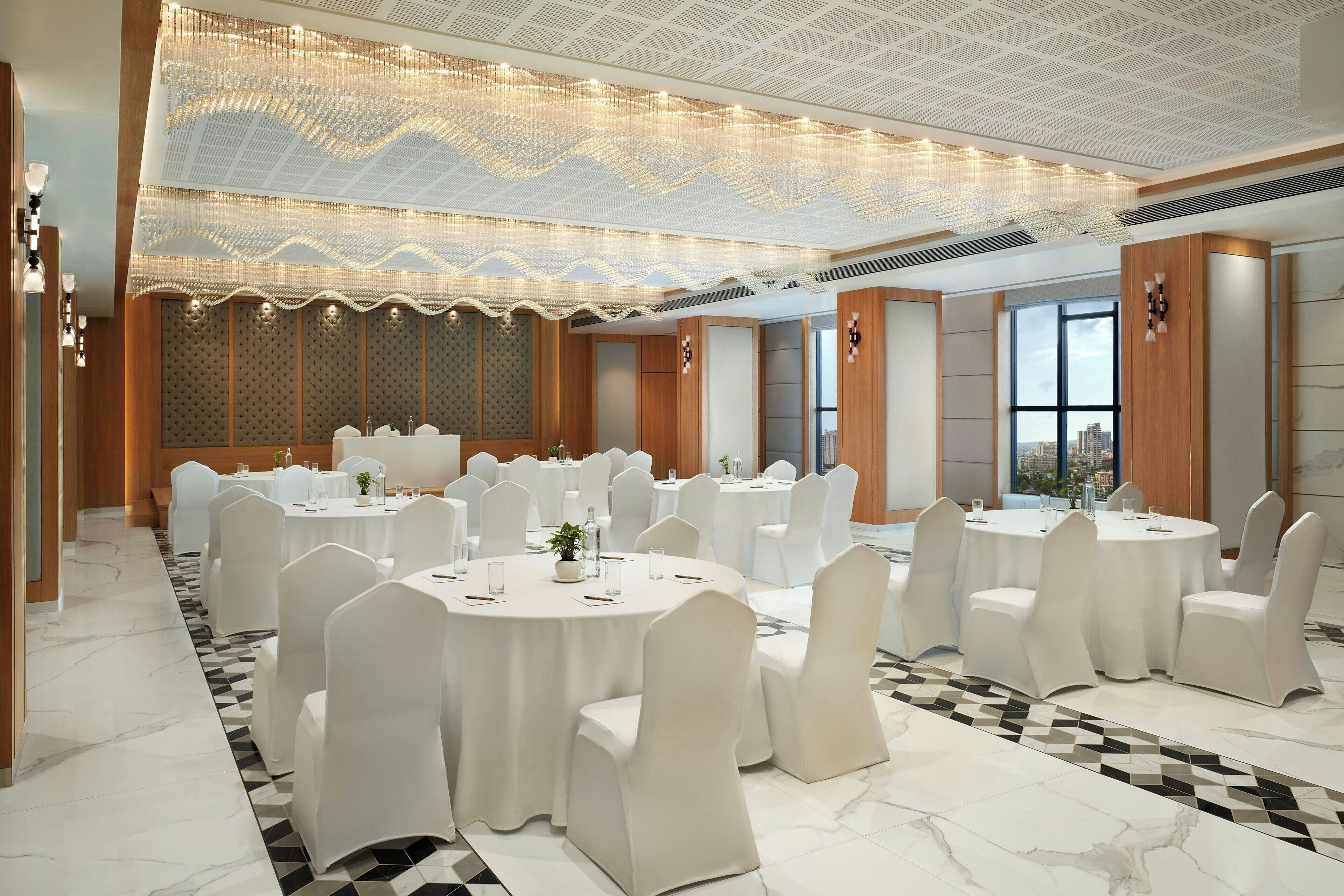 A conference room with round tables, white chairs, and a patterned ceiling.