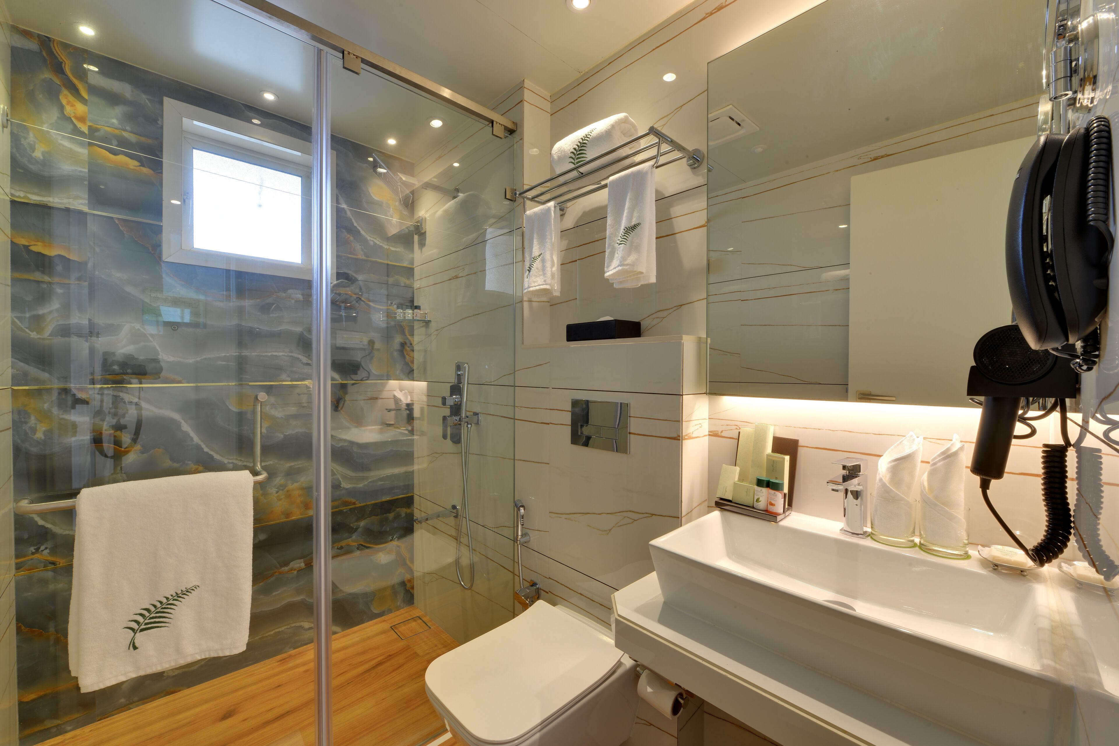 Un baño moderno con cabina de ducha de vidrio, inodoro blanco y tocador con espejo.