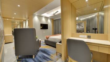 A modern hotel room with a bed, desk, chair, and a large mirror.