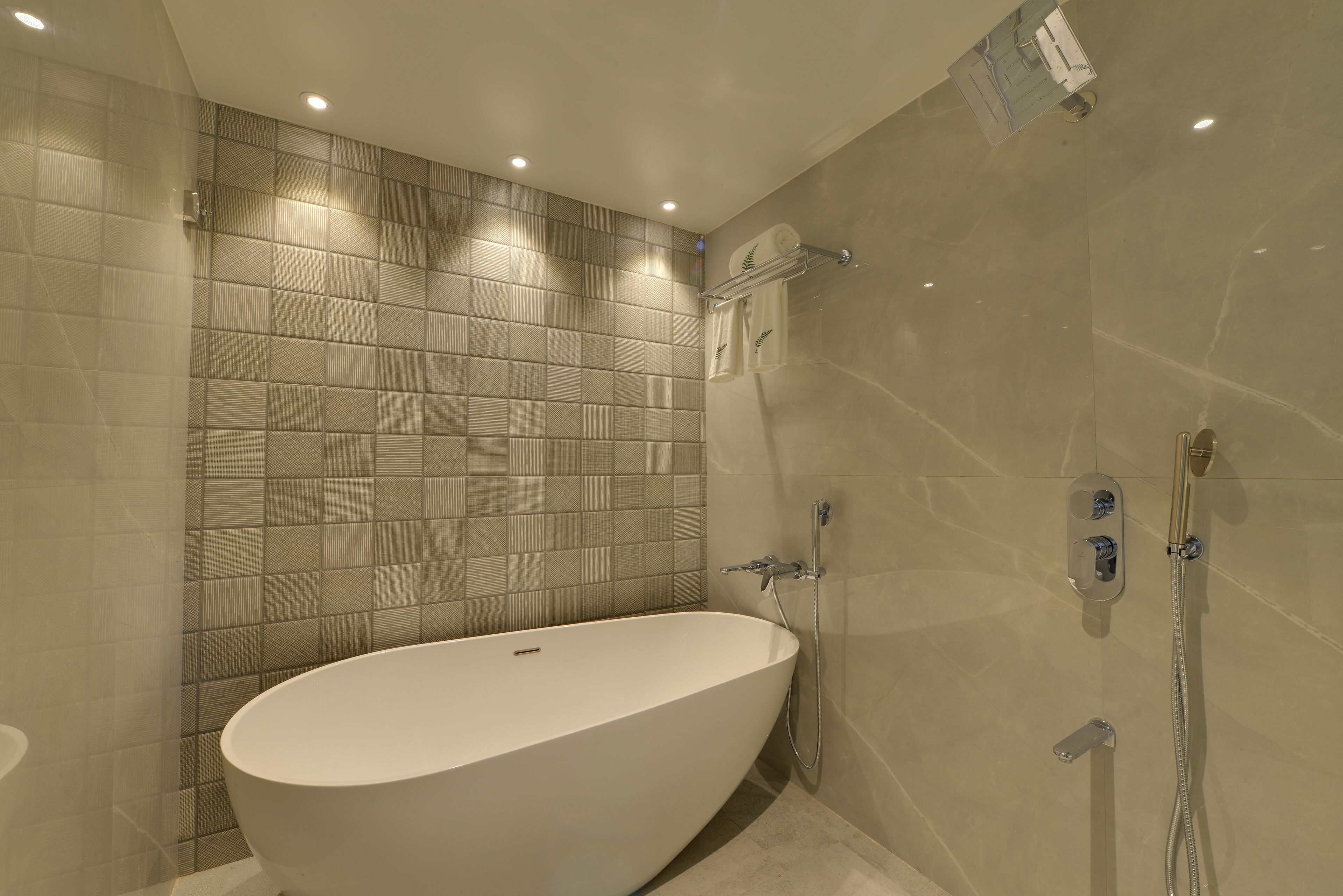 Un baño moderno con una bañera independiente, una zona de ducha y una pared revestida de azulejos.