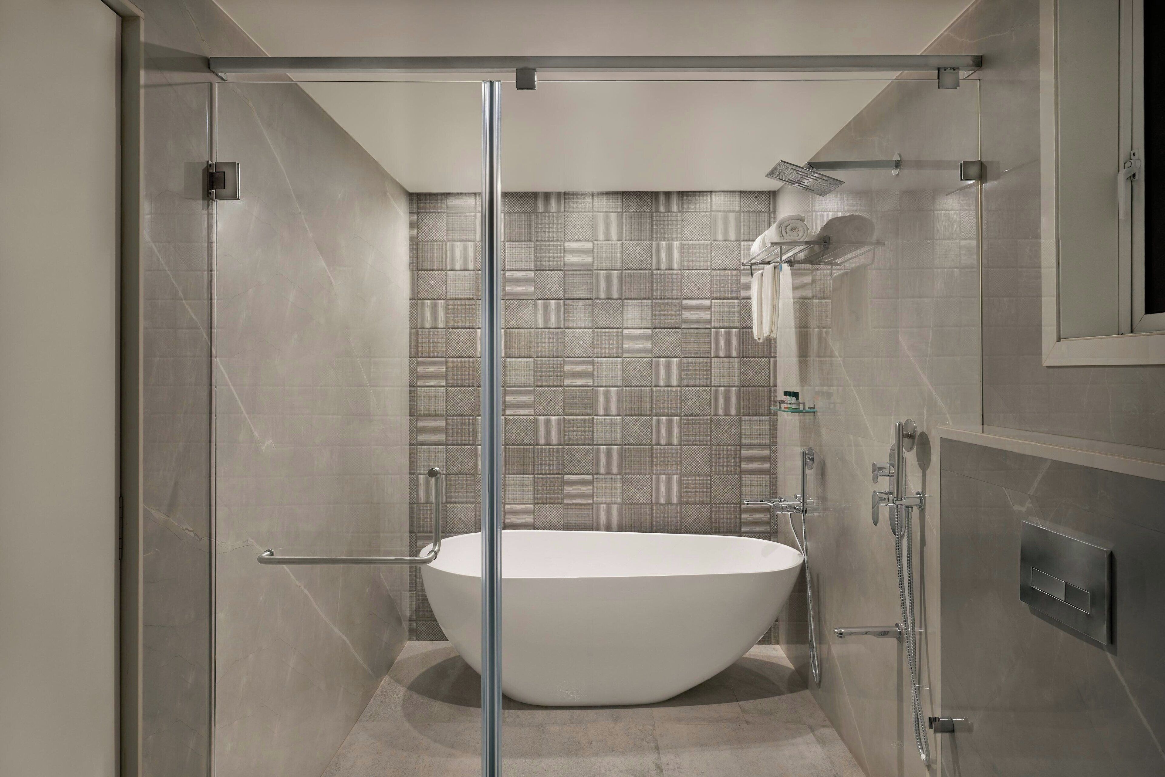 A modern bathroom with a freestanding bathtub, glass shower enclosure, and a tiled shower area.