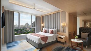A modern hotel room with a large bed, a nightstand, a round table, and a view of the cityscape. - The Fern Residency Mumbai, Mira Road, Series by Marriott (Mumbai)