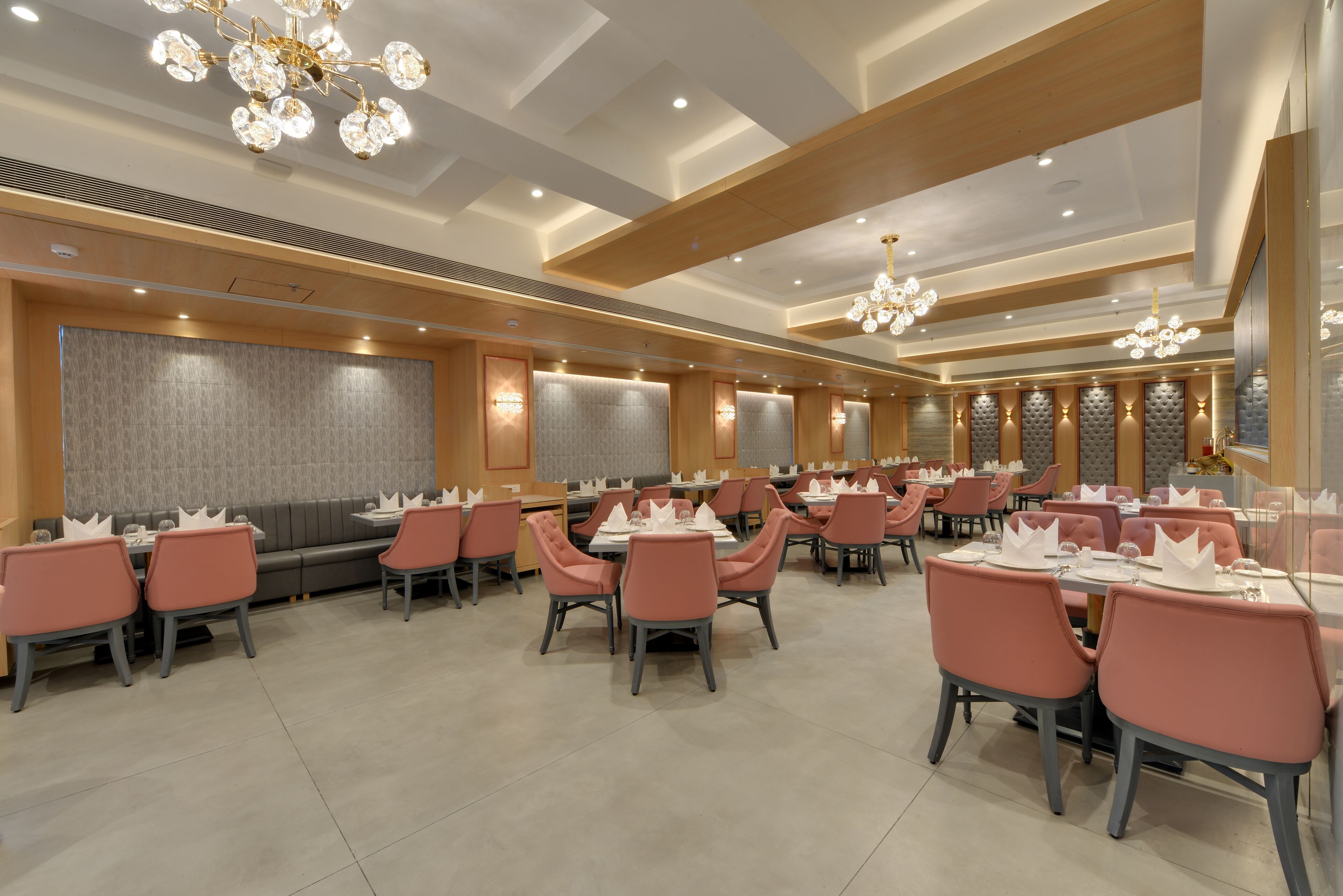 Un restaurante espacioso con múltiples mesas y sillas, elegantes candelabros y un diseño de interiores moderno.